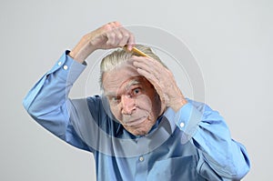 Active elderly man combing his hair with a comb