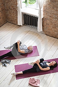 Active elderly people working out on the exercise mats at home