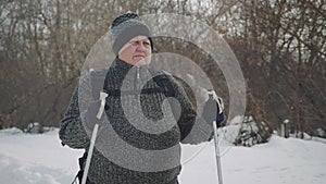 Active an elderly woman engaged in Nordic walking with sticks in the winter forest. Healthy lifestyle concept. Mature