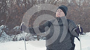 Active an elderly woman engaged in Nordic walking with sticks in the winter forest. Healthy lifestyle concept. Mature