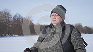 Active an elderly woman engaged in Nordic walking with sticks in the winter forest. Healthy lifestyle concept. Mature