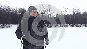 Active an elderly woman engaged in Nordic walking with sticks in the winter forest. Healthy lifestyle concept. Mature