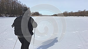 Active an elderly woman engaged in Nordic walking with sticks in the winter forest. Healthy lifestyle concept. Mature