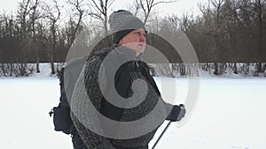 Active an elderly woman engaged in Nordic walking with sticks in the winter forest. Healthy lifestyle concept. Mature