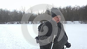 Active an elderly woman engaged in Nordic walking with sticks in the winter forest. Healthy lifestyle concept. Mature