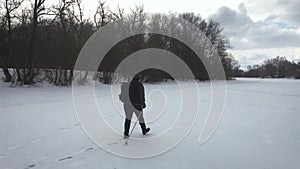 Active an elderly woman engaged in Nordic walking with sticks in the winter forest. Healthy lifestyle concept. Mature