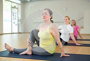 Active elderly woman practicing yoga at group
