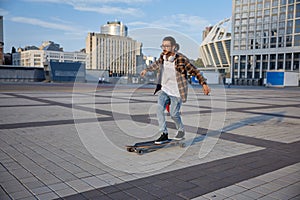 Active energetic stylish hipster guy riding skateboard on city street
