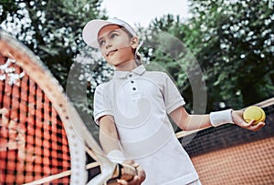 Active exercise for kids on tennis court. Portrait of sporty little girl on tennis court. Summer activities for children.Child