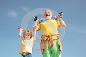 Active family enjoy sport and fitness. Funny old senior man and kid boy with dumbbells. Grandfather and child do morning