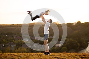 Active family. Father and daughter have fun together. Dad throws daughter up in sky.