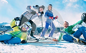 Koncept aktívnej rodinnej dovolenky. Skupina oblečená lyžiarske oblečenie úprimne sa usmieva a smeje sa pózuje pre fotografiu na lyžiarskom kopci na snehu