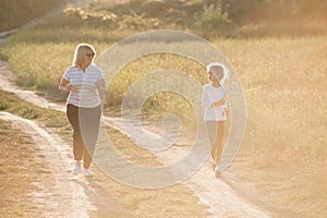 Active fat female grandmother walking outdoors together with little thin girl during running workout