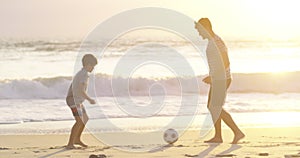 Active father and son playing soccer at the beach at sunset, having fun while keeping fit and bonding. Parent being