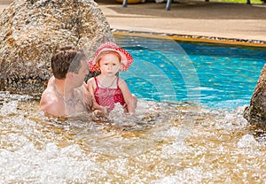 Active father teaching his toddler daughter to swim in pool