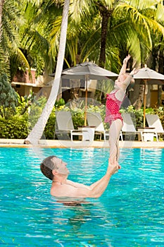 Active father teaching his toddler daughter to swim in pool on tropical resort