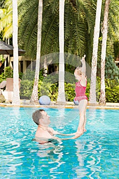 Active father teaching his toddler daughter to swim in pool on tropical resort