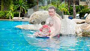 Active father teaching his toddler daughter to swim in pool on tropical resort