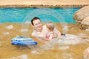 Active father teaching his toddler daughter to swim in pool on tropical resort