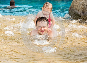 Active father teaching his toddler daughter to swim in pool on tropical resort