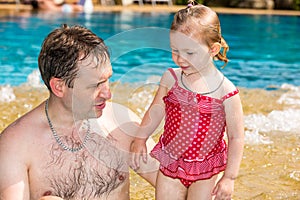 Active father teaching his toddler daughter to swim in pool on tropical resort.