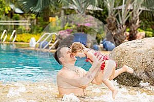 Active father teaching his toddler daughter to swim in pool on tropical resort.