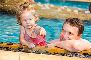 Active father teaching his toddler daughter to swim in pool on tropical resort