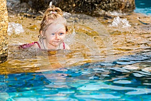 Active father teaching his toddler daughter to swim in pool on tropical resort.