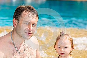 Active father teaching his toddler daughter to swim in pool on tropical resort.