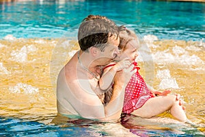 Active father teaching his toddler daughter to swim in pool on tropical resort.