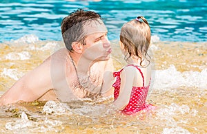 Active father teaching his toddler daughter to swim in pool on tropical resort.