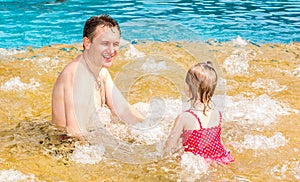 Active father teaching his toddler daughter to swim in pool on tropical resort.