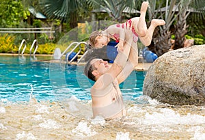 Active father teaching his toddler daughter to swim in pool on tropical resort