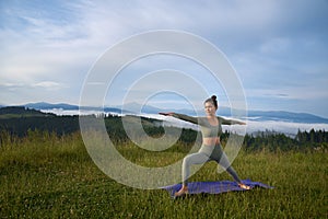 Active female person doing yoga exercises outdoors