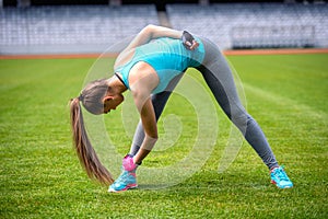 Active female runner stretching and relaxing muscles after hard workout. Fitness and sports concept