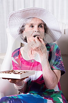 Active female senior earing chocolate candy