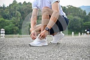 Active and fit Asian athletic man in sportswear tying his running shoe laces. close-up