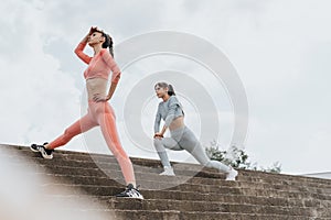 Active fit girls workout together outdoors on urban stairs, showcasing their confident and sporty lifestyle.