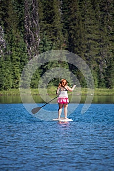 Active fit woman on a Stand up paddleboard boating on Todd Lake Oregon