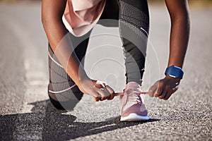 Active and fit woman tying the laces of her sneakers for exercise outdoors. Athlete fastening her shoes to get ready for