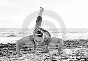 Active fitness woman in sport clothes on beach doing pushups