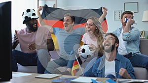 Active German football team fans watching match on tv at home, celebrate victory