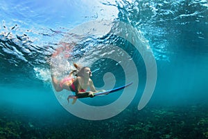 Active girl in bikini in dive action on surf board