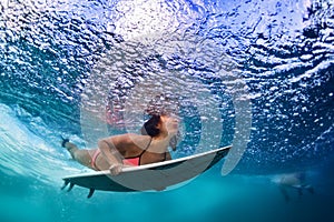 Active girl in bikini in dive action on surf board