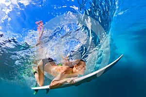 Active girl in bikini in dive action on surf board