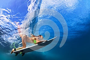 Active girl in bikini in dive action on surf board