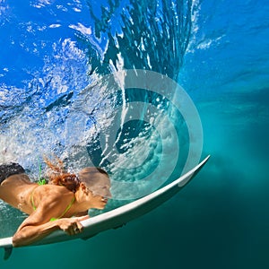 Active girl in bikini in dive action on surf board