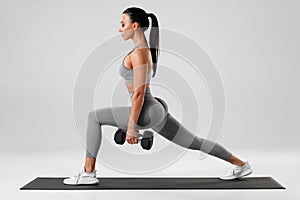Active girl doing lunges exercises for leg muscle workout training. Fitness woman doing front forward one leg step lunge exercise