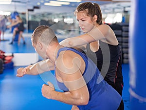 Active girl exercise fight with man trainer in gym