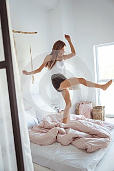 Active girl jumping on her bed with pleasure